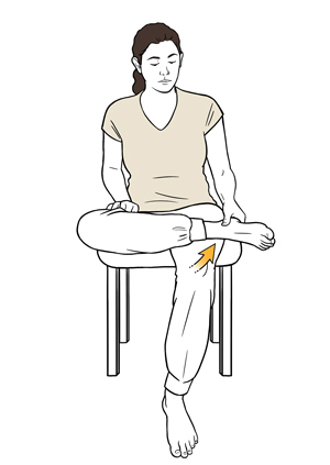 Woman sitting on chair with one ankle resting on opposite knee doing figure 4 stretch.