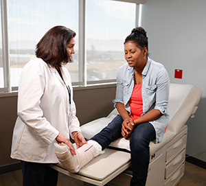 Un proveedor de atención médica examina el yeso en la pierna de una mujer.