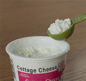 Closeup of tablespoon measuring out cottage cheese.