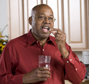 Man taking pill with glass of water.