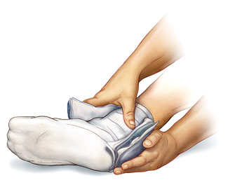 Primer plano de manos que sostienen una compresa de hielo alrededor de un tobillo. Calcetín que cubre el pie y el tobillo.