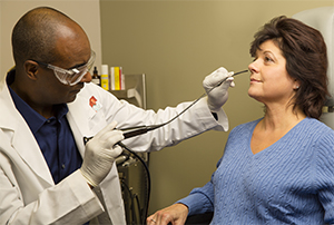 Proveedor de atención médica preparándose para insertar un endoscopio en la nariz de una mujer.