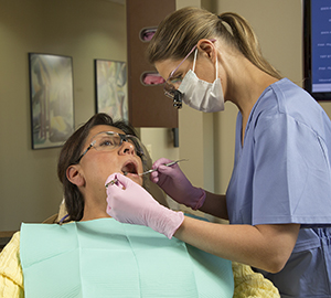 Un proveedor de atención médica dental limpiándole los dientes a una mujer.