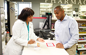 Un farmacéutico habla con una hombre en el mostrador de la farmacia.